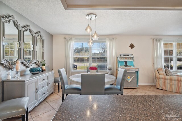 dining area featuring light tile patterned floors, baseboards, and a textured ceiling