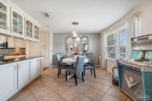 dining space with a chandelier, visible vents, baseboards, and light tile patterned flooring