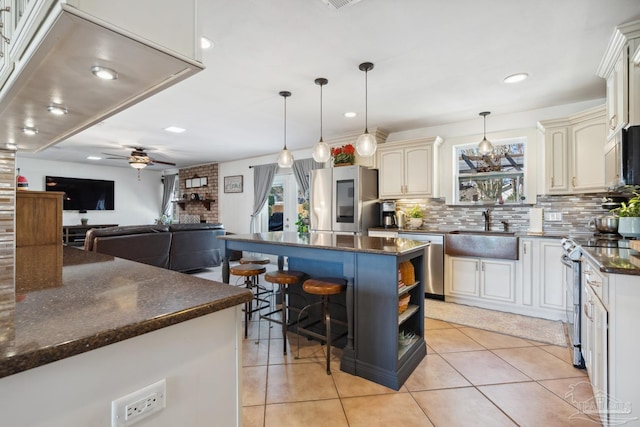 kitchen featuring a healthy amount of sunlight, appliances with stainless steel finishes, cream cabinetry, and a sink