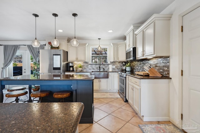 kitchen featuring appliances with stainless steel finishes, a sink, decorative backsplash, and a kitchen breakfast bar