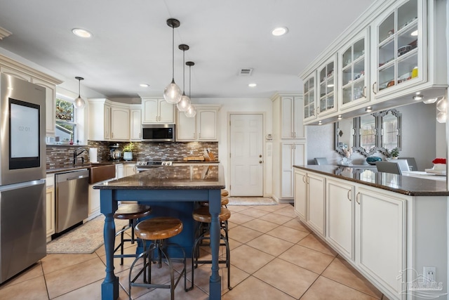 kitchen with stainless steel appliances, tasteful backsplash, light tile patterned flooring, and glass insert cabinets