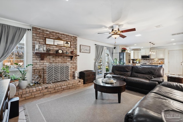 living room with ceiling fan, visible vents, a fireplace, and light tile patterned flooring