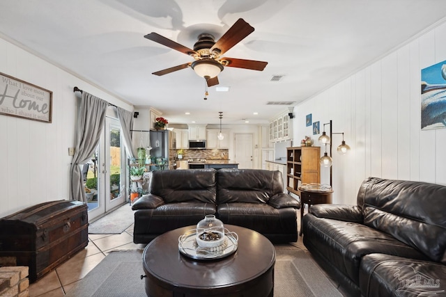 living area featuring light tile patterned floors, ornamental molding, visible vents, and a ceiling fan