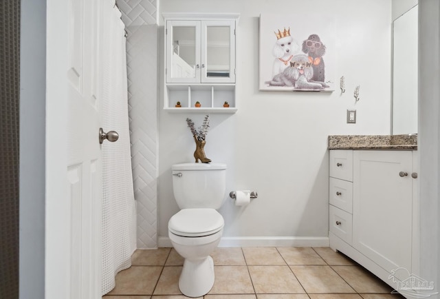 bathroom with tile patterned flooring, baseboards, vanity, and toilet