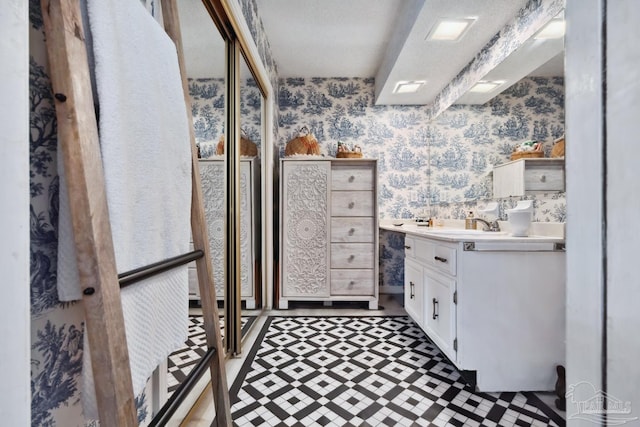 bathroom with wallpapered walls and vanity