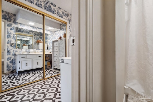 bathroom with tile patterned floors, vanity, and wallpapered walls