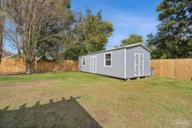 view of yard featuring an outbuilding, a storage unit, and a fenced backyard