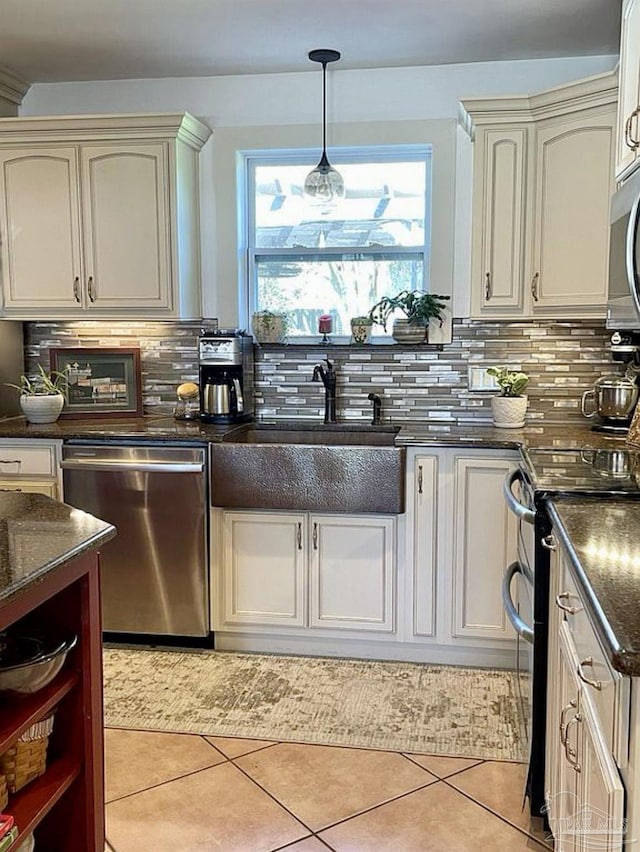 kitchen with light tile patterned floors, stainless steel appliances, a sink, hanging light fixtures, and backsplash