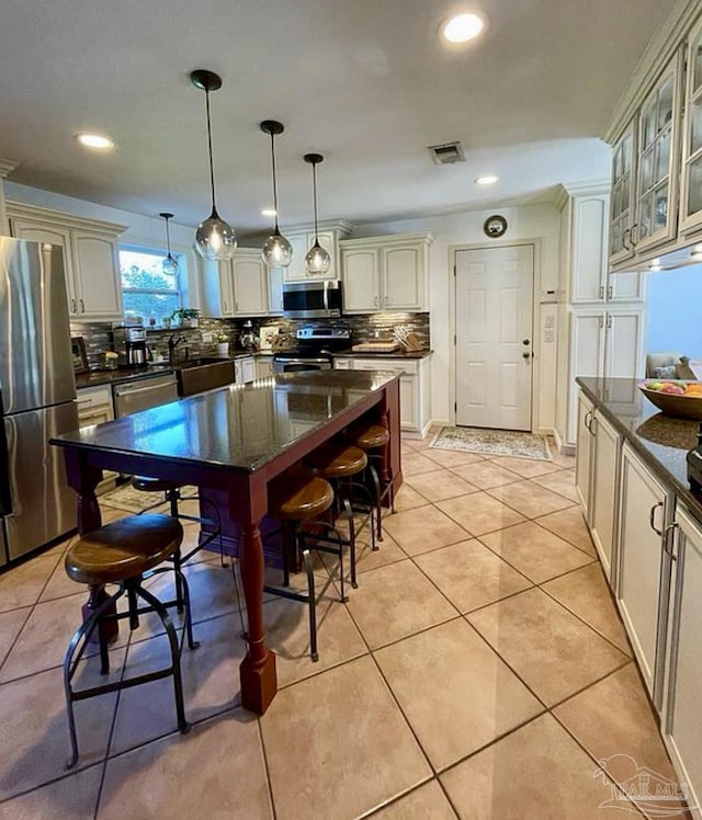 kitchen featuring appliances with stainless steel finishes, light tile patterned flooring, glass insert cabinets, and decorative backsplash