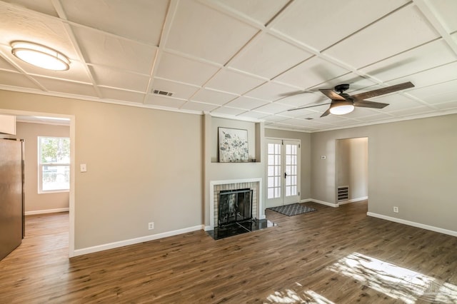 unfurnished living room with ceiling fan, dark hardwood / wood-style floors, a brick fireplace, and a wealth of natural light