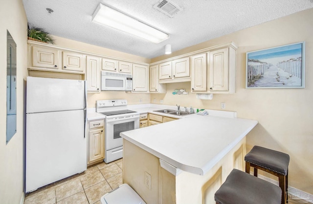 kitchen with white appliances, a peninsula, light countertops, a kitchen bar, and a sink