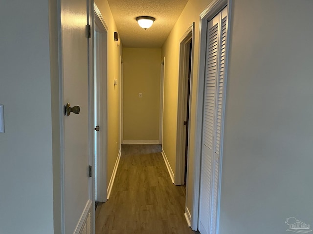 corridor with dark wood-type flooring and a textured ceiling