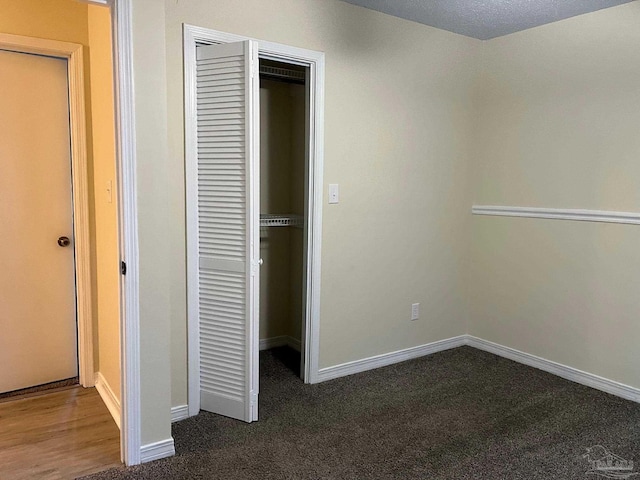 unfurnished bedroom with dark carpet and a closet