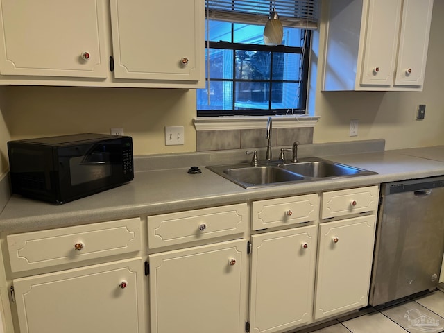 kitchen featuring sink, light tile patterned floors, stainless steel dishwasher, and white cabinets