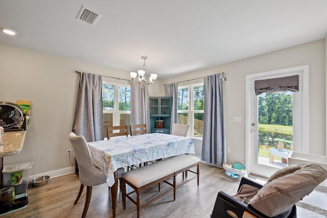 dining room featuring baseboards, light wood-style flooring, visible vents, and a notable chandelier