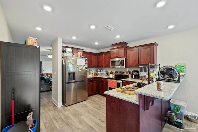 kitchen with light stone counters, stainless steel appliances, light wood-style flooring, dark brown cabinets, and a peninsula