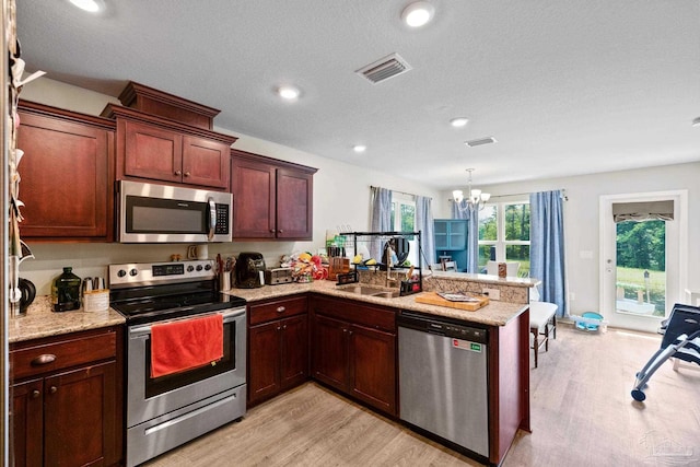 kitchen featuring stainless steel appliances, visible vents, a sink, a chandelier, and a peninsula