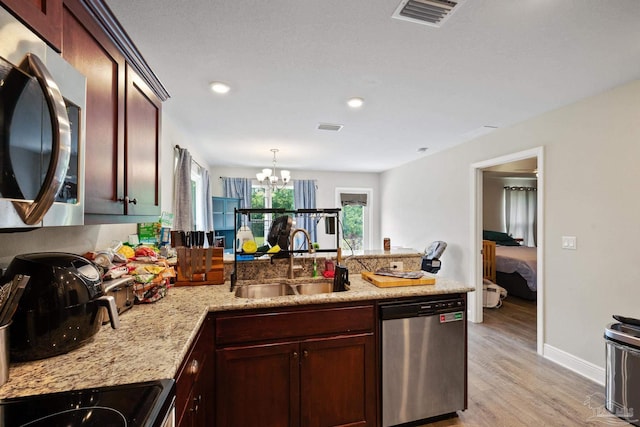 kitchen featuring stainless steel appliances, a peninsula, a sink, visible vents, and light wood-style floors