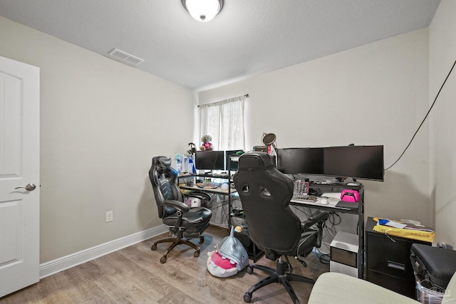 office space with wood finished floors, visible vents, and baseboards