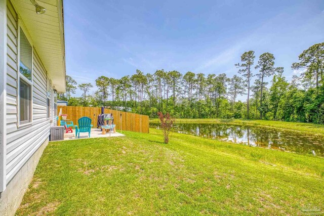 view of yard featuring a patio area, a water view, and fence