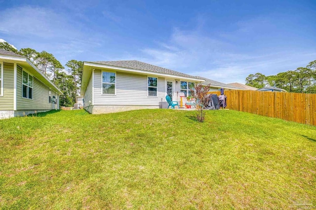 rear view of house with a yard and fence