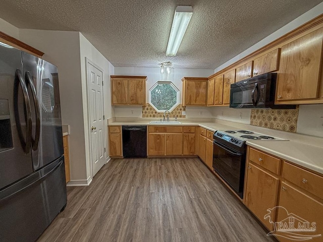 kitchen featuring hardwood / wood-style floors, backsplash, black appliances, sink, and a textured ceiling