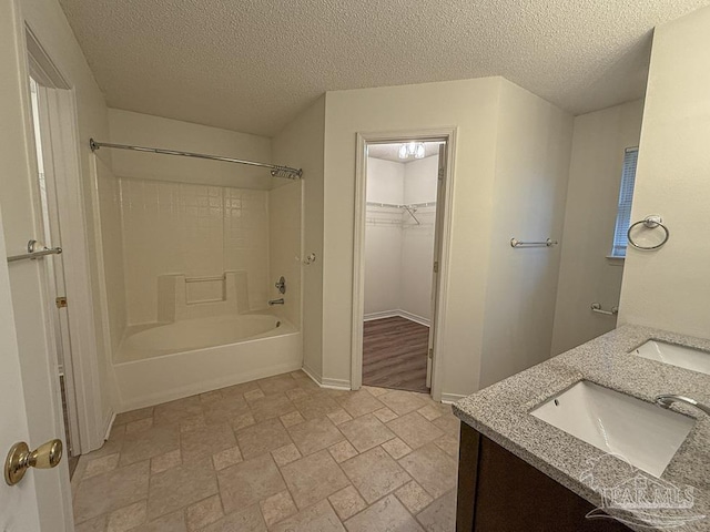 bathroom with vanity, a textured ceiling, and bathtub / shower combination