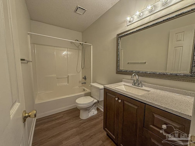 full bathroom with hardwood / wood-style floors, vanity, shower / washtub combination, toilet, and a textured ceiling