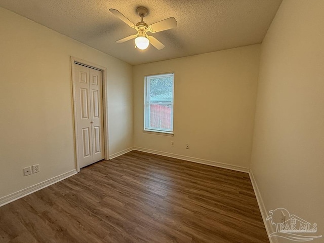 unfurnished room featuring a textured ceiling, ceiling fan, and dark wood-type flooring