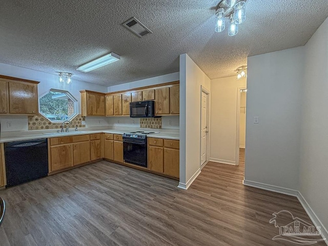 kitchen featuring a textured ceiling, sink, hardwood / wood-style flooring, and black appliances