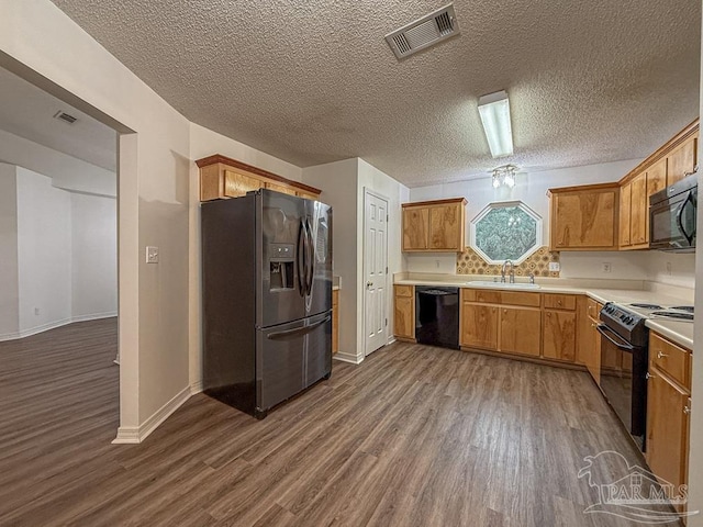 kitchen featuring wood-type flooring, sink, a textured ceiling, and black appliances