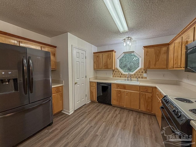 kitchen with hardwood / wood-style floors, sink, a textured ceiling, and black appliances