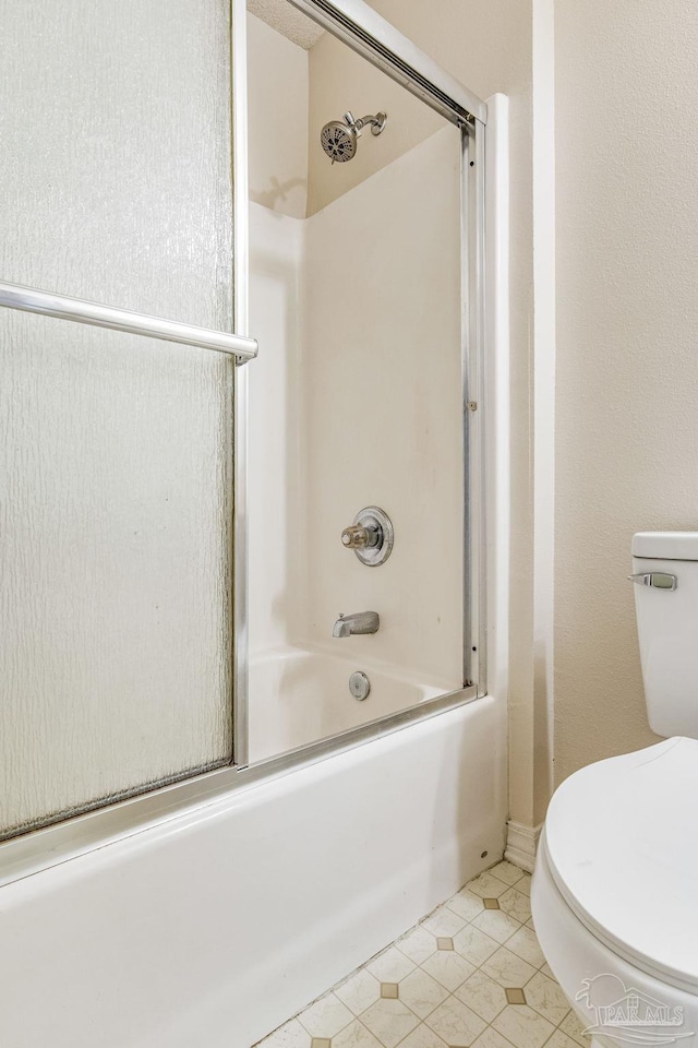 bathroom with shower / bath combination with glass door, tile patterned flooring, and toilet