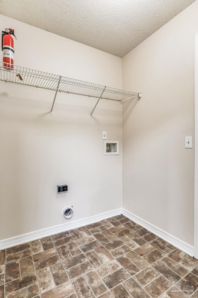 washroom featuring hookup for an electric dryer, hookup for a washing machine, and a textured ceiling