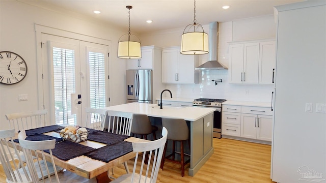 kitchen featuring white cabinets, plenty of natural light, wall chimney exhaust hood, and appliances with stainless steel finishes