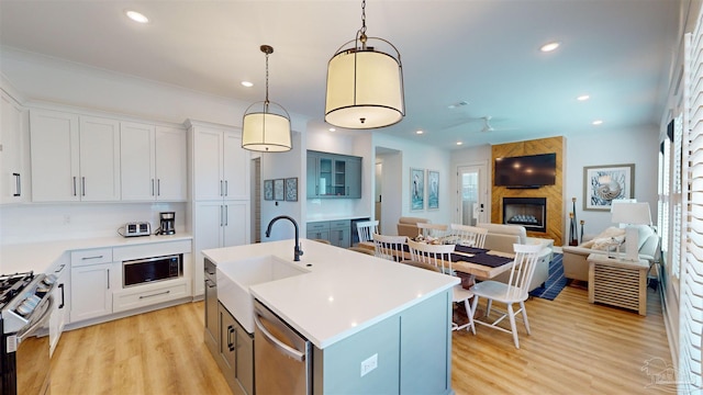 kitchen featuring white cabinetry, an island with sink, decorative light fixtures, and appliances with stainless steel finishes