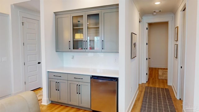 bar featuring gray cabinets, light hardwood / wood-style flooring, tasteful backsplash, and stainless steel dishwasher