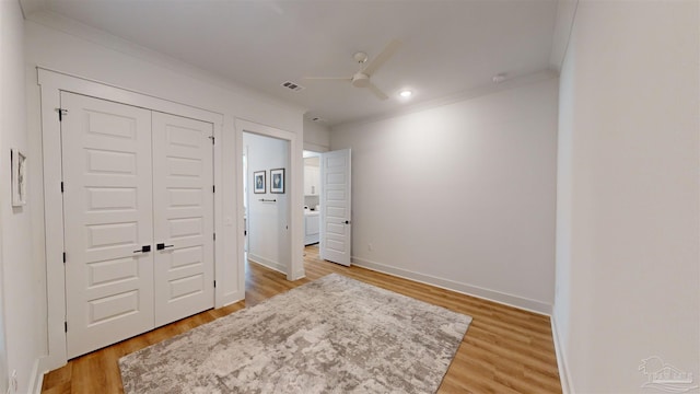 bedroom with hardwood / wood-style flooring, ceiling fan, crown molding, and a closet