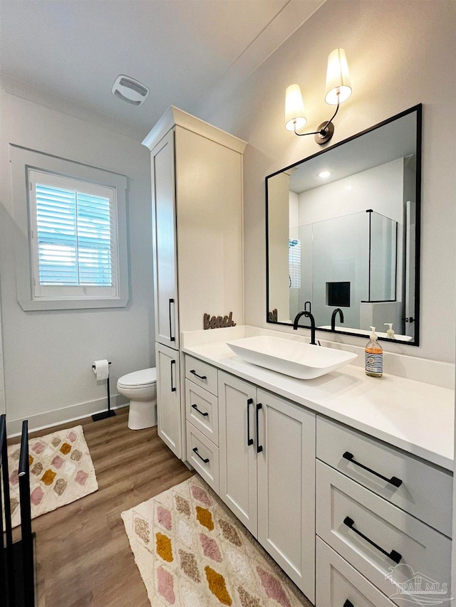 bathroom featuring hardwood / wood-style floors, vanity, toilet, and a shower with door