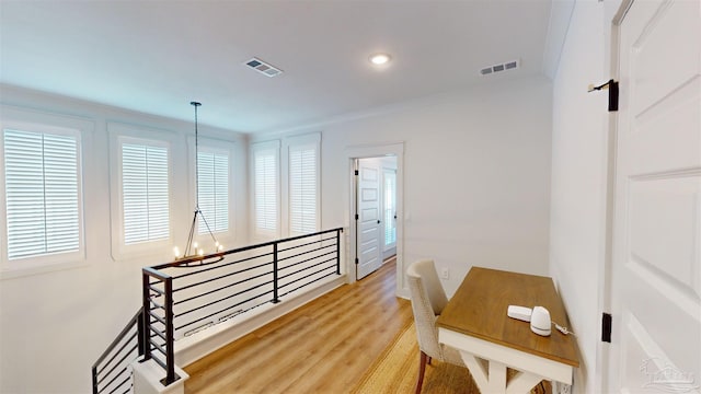 hallway featuring hardwood / wood-style floors, ornamental molding, and a notable chandelier