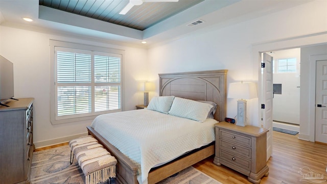 bedroom featuring a raised ceiling, ceiling fan, and light hardwood / wood-style floors