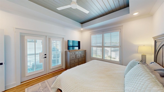 bedroom featuring french doors, light hardwood / wood-style flooring, ceiling fan, a tray ceiling, and wood ceiling