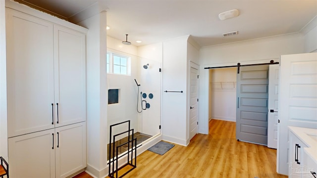 interior space featuring a barn door, light hardwood / wood-style floors, and ornamental molding