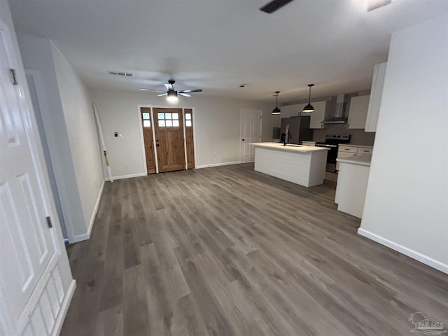 kitchen with visible vents, an island with sink, dark wood-style floors, stainless steel electric stove, and wall chimney range hood