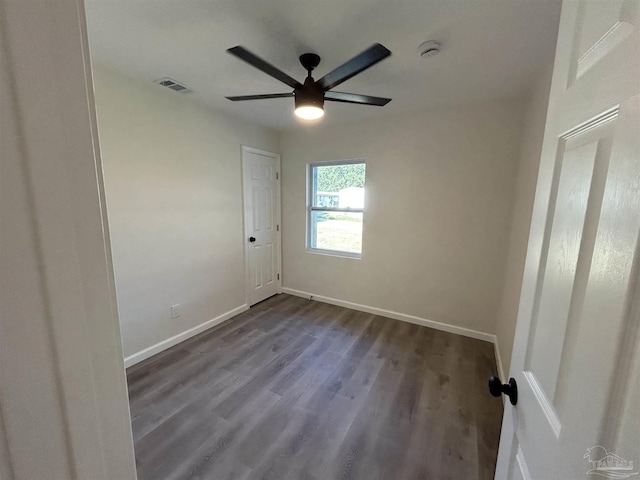 unfurnished room with dark wood-style floors, baseboards, visible vents, and a ceiling fan