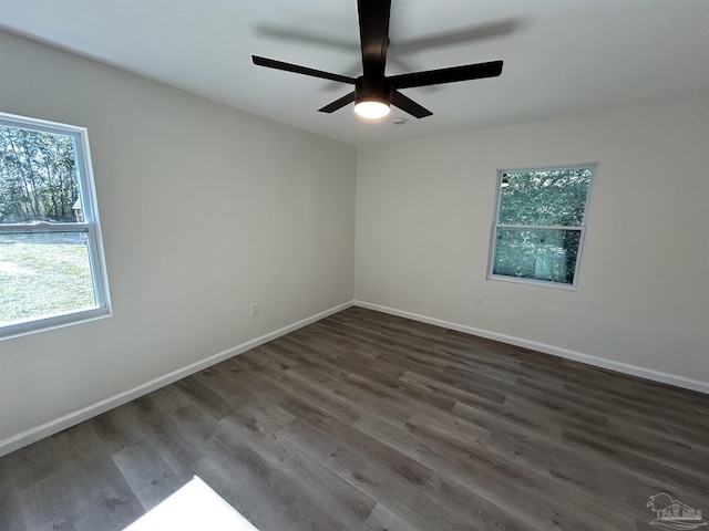 empty room featuring a ceiling fan, baseboards, and dark wood-style flooring