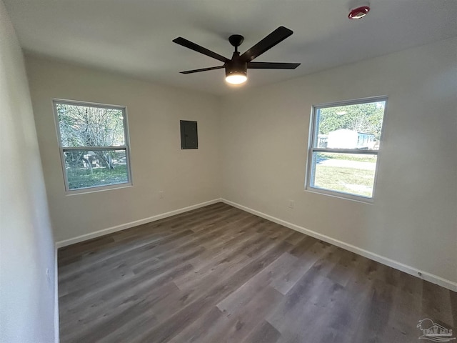 spare room featuring dark wood-style flooring, electric panel, ceiling fan, and baseboards