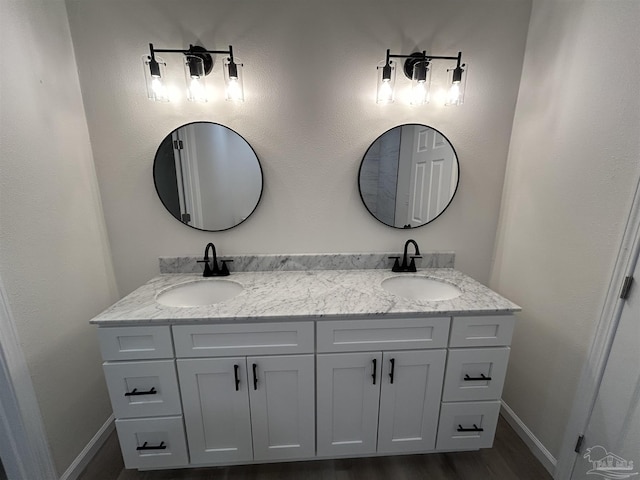 full bathroom with double vanity, a sink, and baseboards