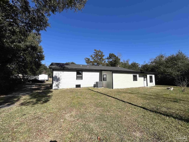 rear view of house with cooling unit and a yard