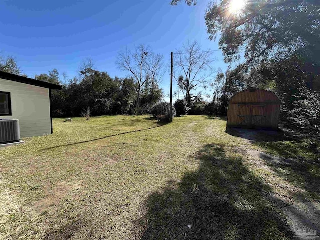 view of yard featuring an outbuilding, a storage shed, and central AC unit